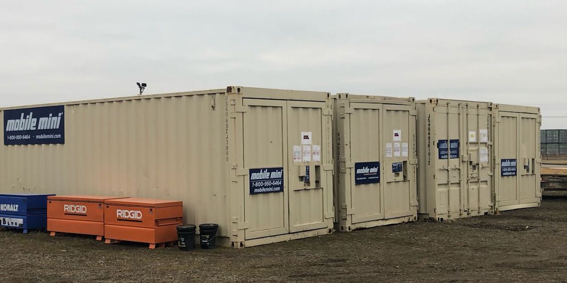 Four mobile mini portable storage units lined up next to one another